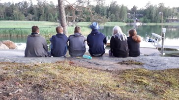 Isoshaku Nuoria istumassa rivissä leirikeskuksen kalliolla meren rannalla.