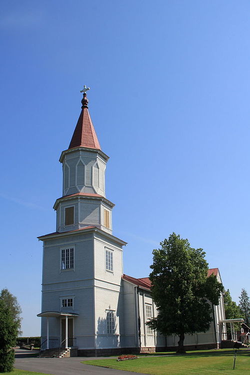 Kesäinen kuva Mellilän kirkosta. Kuva on otettu pääoven suunnasta, sisäänkäynnin yläpuolella kohoaa kirkon torni. Mellilän kirkko on puuverhoiltu, vaalean siniharmaan värinen, katto on punainen.